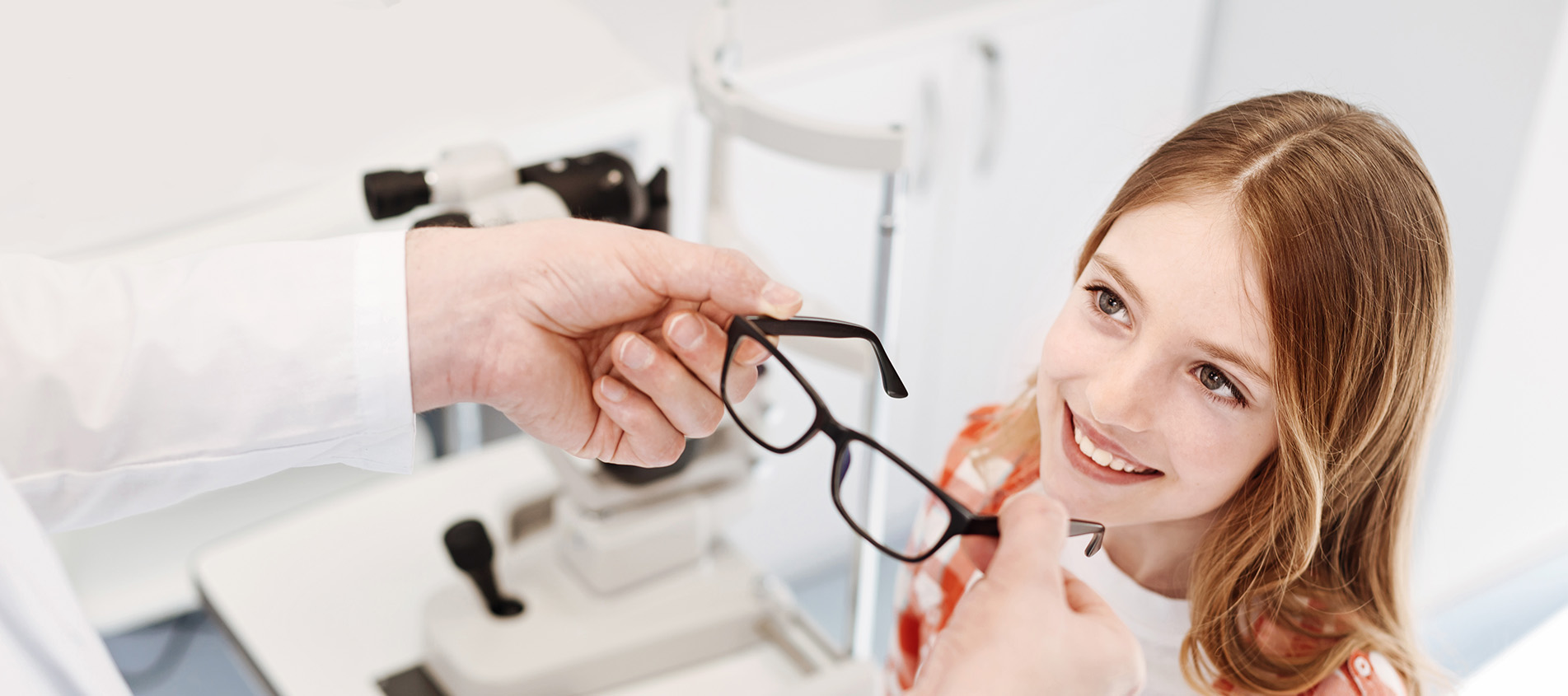 Optometreist Fitting Young Girl With Eyeglasses
